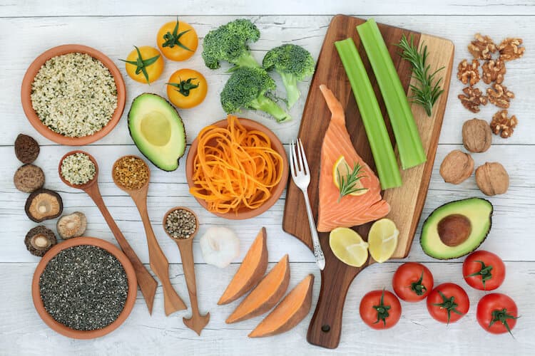 A top view of food for memory, including fish, vegetables, seeds and nuts on a rustic background.